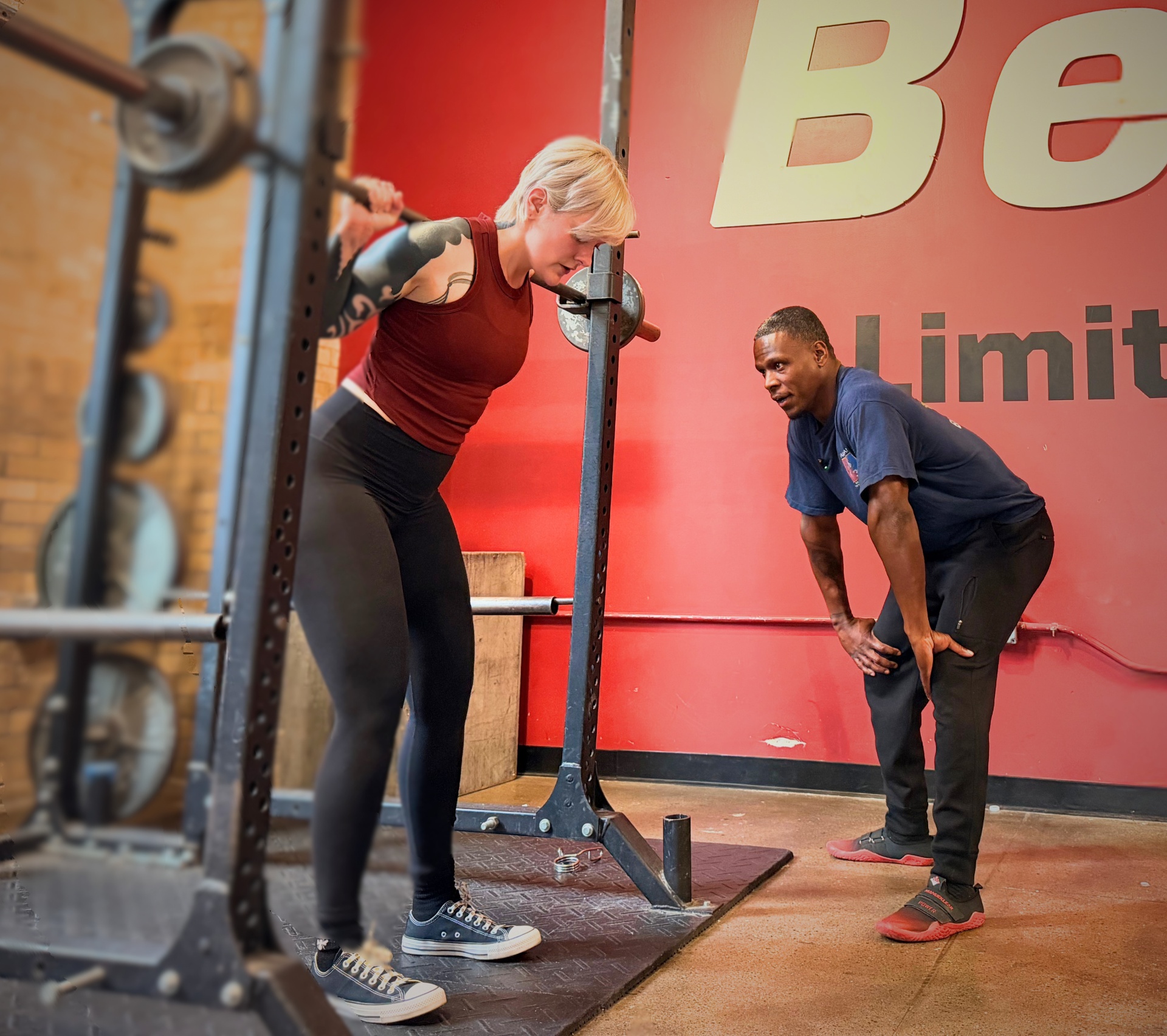 Coach observing a client during a barbell squat in the gym